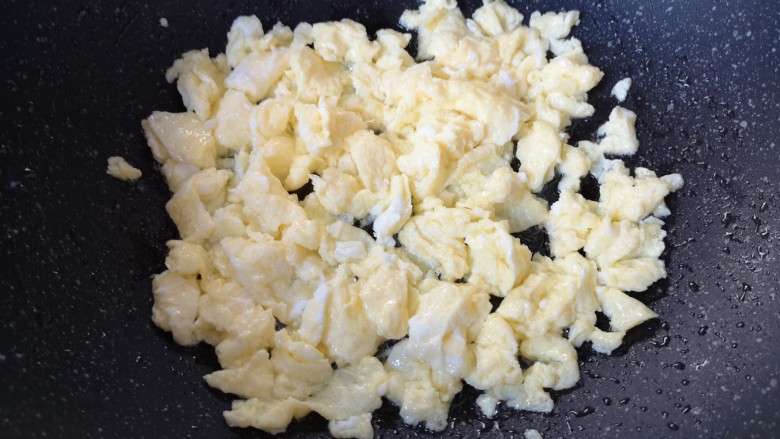 蚕豆炒鸡蛋,将鸡蛋炒熟后用铲子敲成小块,盛出备用。