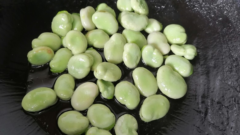 韭菜炒蚕豆,锅内放油烧热放入蚕豆翻炒