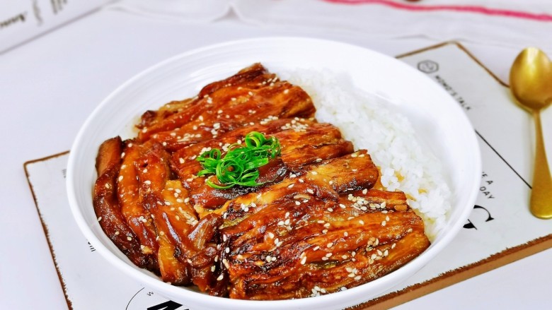茄子盖浇饭,米饭装盘,再放上茄子,撒上葱丝。