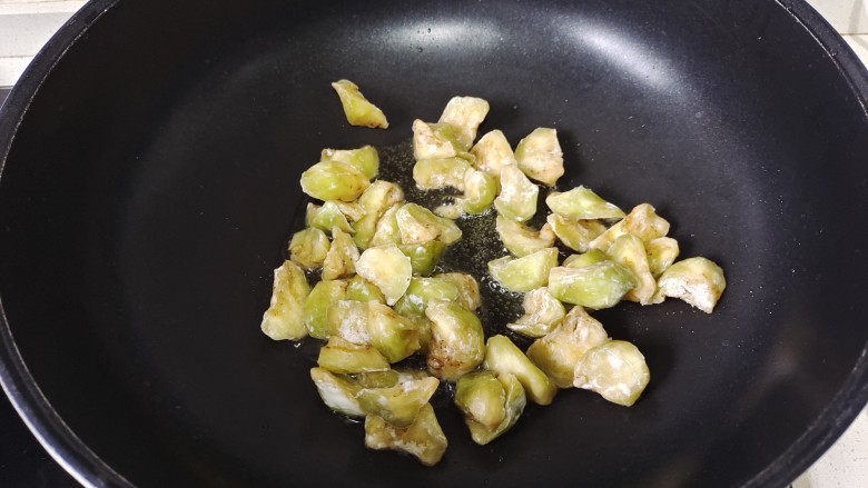 茄子盖浇饭,放入茄子炸二三分钟,加入一些葱花翻炒均匀