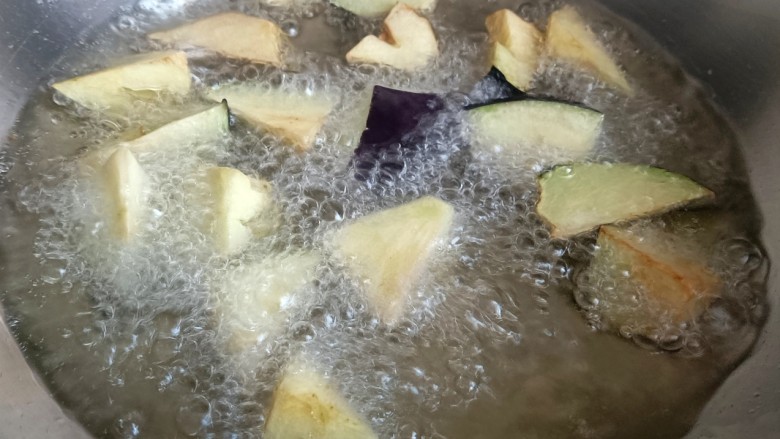 茄子盖浇饭,起锅烧油,家庭炸茄子不需要像饭店倒大半锅油,可以分批次多炸几锅,不然家里消耗少,炸过的油不好消耗。差不多七成热下锅炸,炸到表面有点金黄色就捞出。