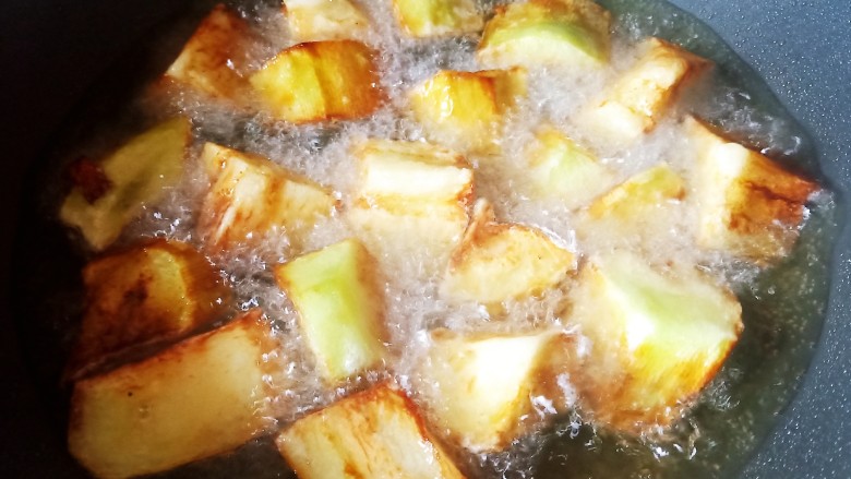 茄子盖浇饭,锅中烧油,油温6成热放入茄子炸。