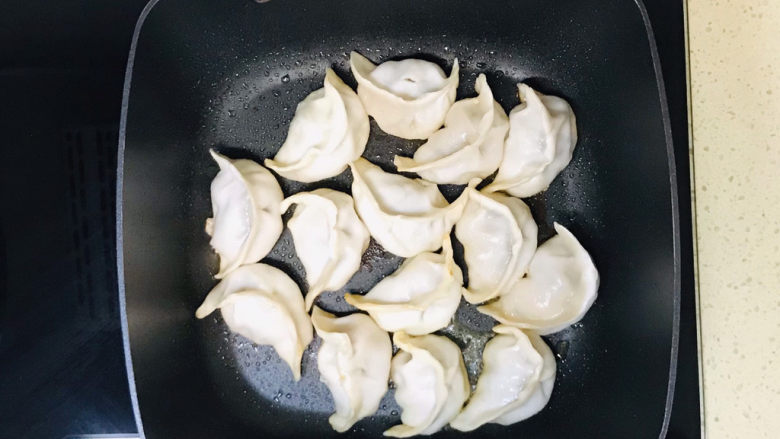 韭菜肉锅贴,盖上锅盖,慢火煎煮至水分蒸干,锅贴蒸熟