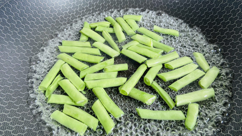豆角牛柳,锅中加入适量清水大火烧开,加入少许盐和食用油。放入豆角焯烫三分钟