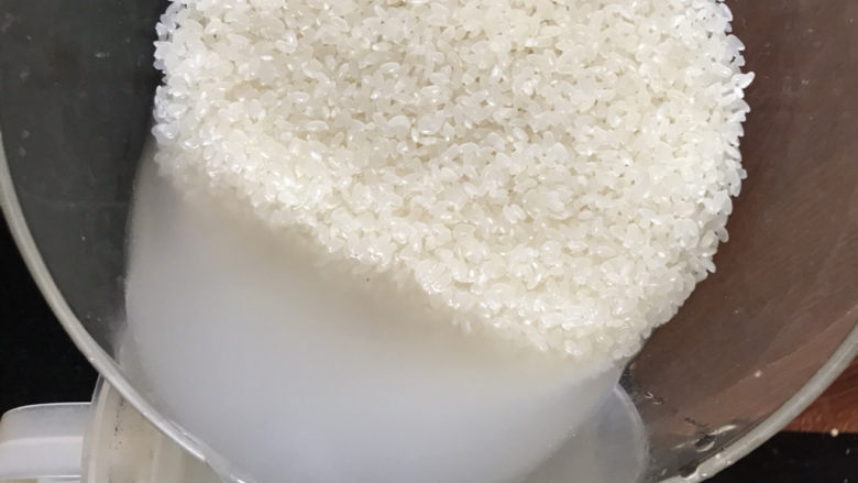 什锦香肠焖饭,浸泡好的大米淘洗干净后倒入电饭煲里,加入漠过手指的水
