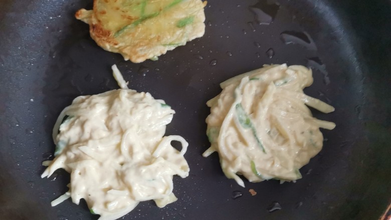 家常土豆饼,平底锅烧热刷油,用手揪一块面团,两手拍扁放入锅中小火烙