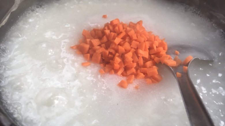 胡萝卜肉末粥,加入胡萝卜碎,拌匀后煮5分钟