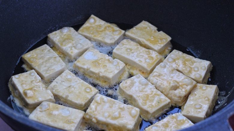 干煸豆腐,平底锅中倒适量食用油烧热,依次放入豆腐块开小火煎制。