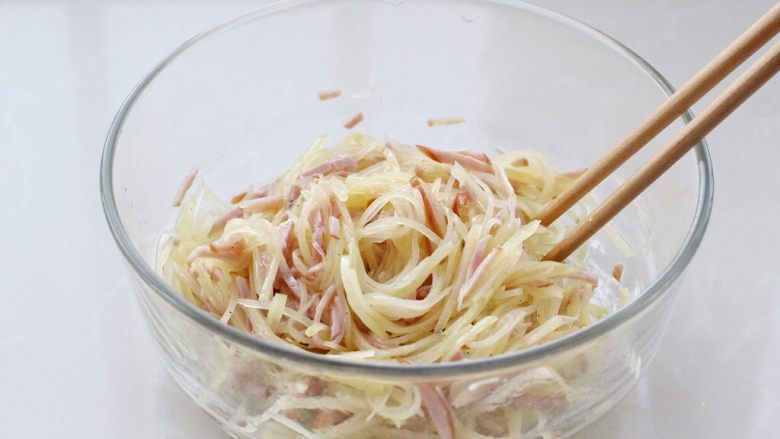家常土豆饼,用筷子将食材与调味料混合搅拌均匀,土豆丝和火腿上面都要裹上蛋清。