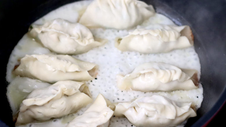 韭菜肉锅贴,看见锅贴底部煎黄的时候,1勺淀粉和1勺面粉加适量清水,搅拌均匀倒入锅中,盖上锅盖煎至底部金黄色即可。