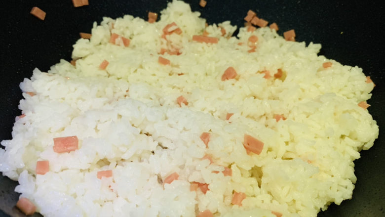 鸡蛋火腿炒饭,锅加食用油,加入米饭,加入火腿粒,翻炒一会