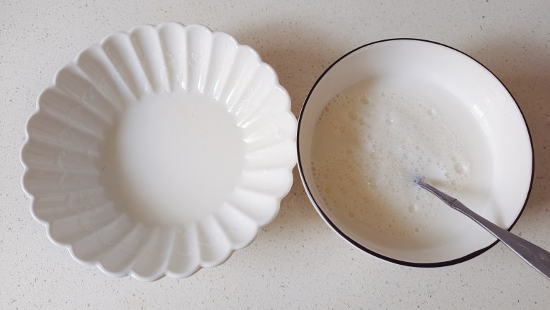 芒果双皮奶,凉好的牛奶用筷子揭开一点奶皮,将牛奶倒入蛋清中混合均匀,牛奶不要全部倒入蛋清中,留一点,防止奶皮贴在碗壁上