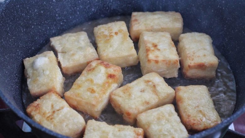 韭菜豆腐,锅中倒入食用油,将裹了淀粉的豆腐块放进去,小火煎至表面呈焦黄状盛出。
