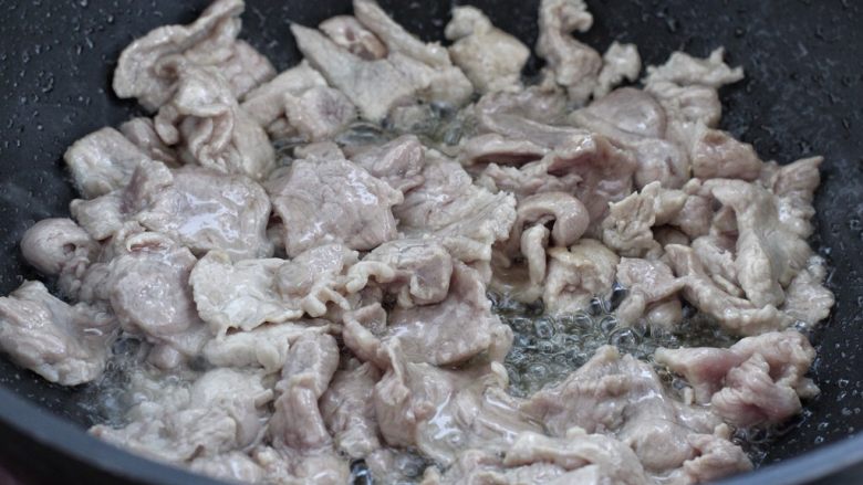 家常炒肉片,锅中倒适量食用油烧热,将腌制好的肉片倒进锅中炒至发白断生状态。