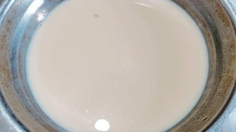 芒果双皮奶,过一遍筛子之后再用筷子挑起奶皮,再把牛奶轻轻地倒回原来的碗里