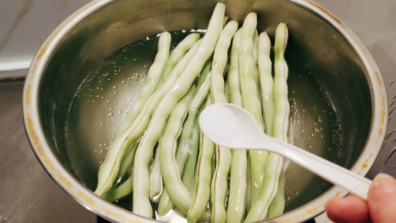 蒜泥拌豆角,放入开水中煮熟,水中加入2克盐和几滴食用油。