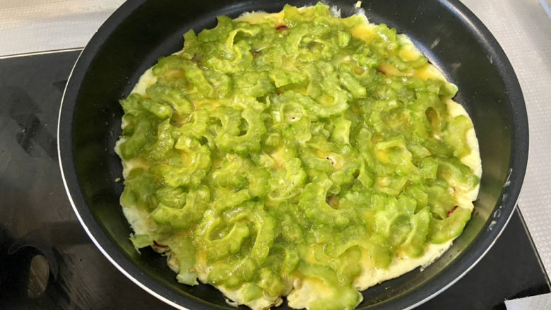 苦瓜摊鸡蛋,用铲子把苦瓜蛋液均匀平铺,小火煎