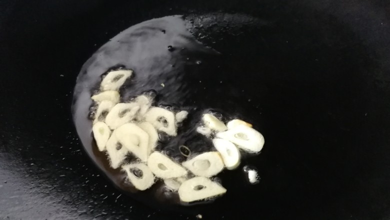 清炒茭白,热锅凉油,油比平时炒菜多点,油热放入蒜片炒香。