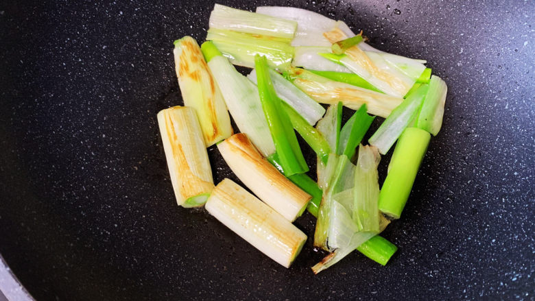 葱烧海参【最正宗做法】,用筷子轻轻翻动葱段,所有面都煎到,其中三段摆盘用的葱煎至金黄就夹出来放好备用,其余的葱段继续煎至微焦。