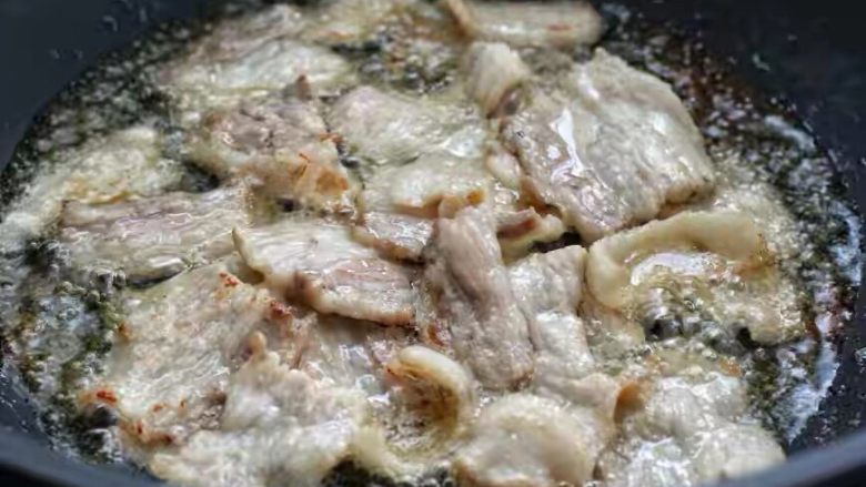 豆角焖肉,锅中倒适量食用油烧热,然后放入五花肉小火煸炒至出油打卷的状态。