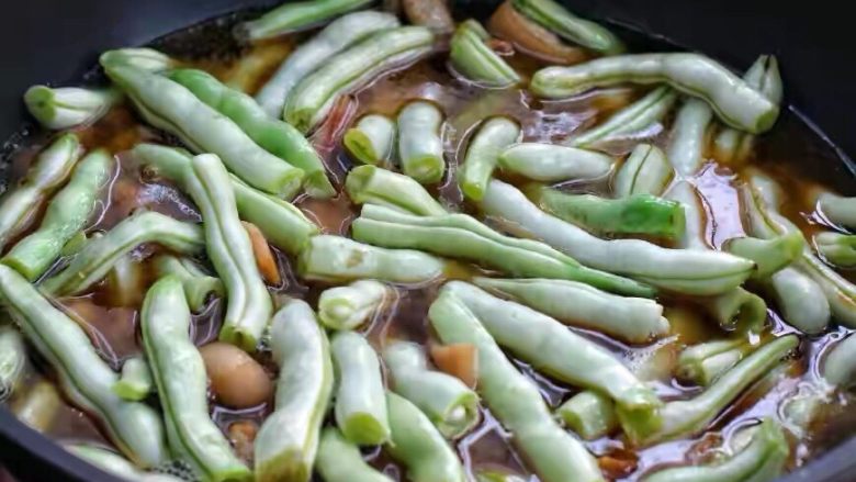 豆角焖肉,添入清水与锅中食材持平,大火煮开后改中火炖煮约十分钟。
