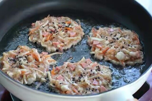 胡萝卜鸡肉饼,平底锅中加适量食用油,尽量选橄榄油或玉米油,用勺子舀取适量肉糜放到锅中摊成饼状,饼不太圆也没关系,在上面撒适量<a style='color:red;display:inline-block;' href='/shicai/ 668'>黑芝麻</a>。