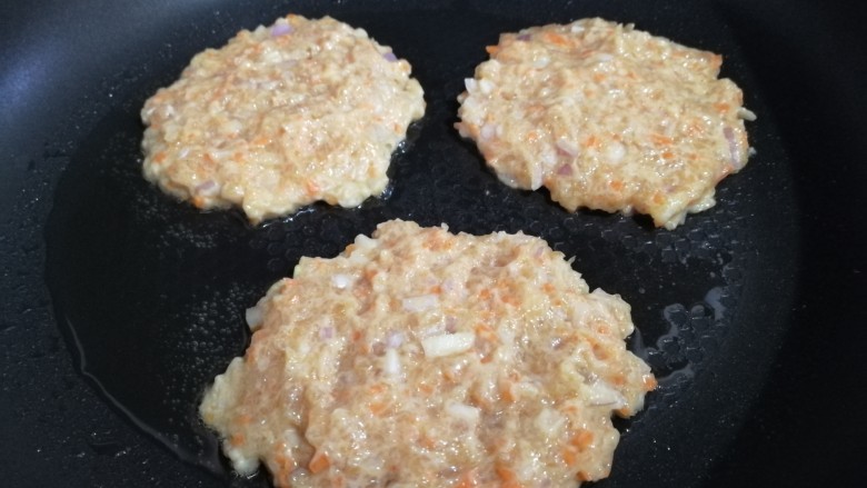 胡萝卜鸡肉饼,平底锅倒入适量油,舀入适量面糊,轻按成饼。