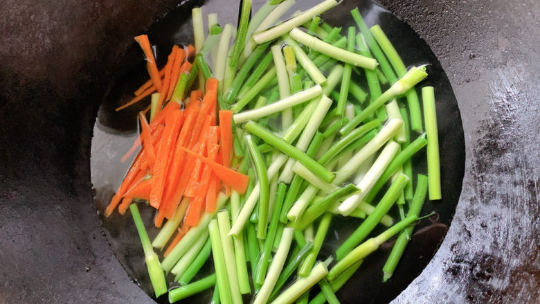 凉拌蒜苗,将胡萝卜去皮切丝、蒜苗切段，锅烧沸水将食材加入其中，焯熟变软后捞出。