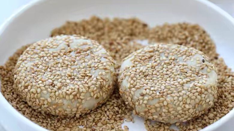 芝麻红薯饼,准备适量的芝麻,把面团放进去均匀的粘满芝麻,再用手轻轻的按压成饼状。