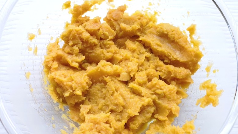 芝麻红薯饼,蒸熟的蜜红薯片从蒸锅里取出晾至温热,放进大一点的盆里,用勺子压成红薯泥。