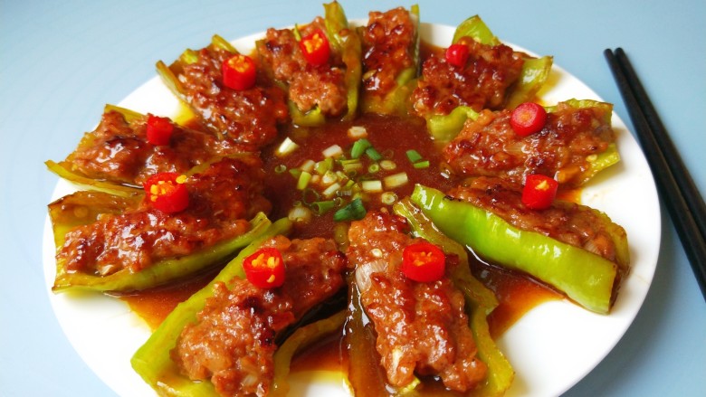 煎酿辣椒,放入盆中,把料汁倒入中间,撒上香葱,红椒粒。
