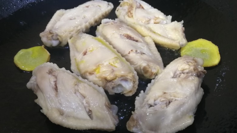 柠香鸡翅,锅中放入适量油,放入姜片和翅中。