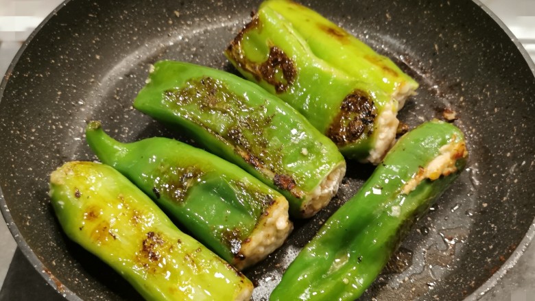 煎酿辣椒,起油锅,放入食用油,油热后将酿好的尖椒码放锅中,小火慢煎,煎至两面焦黄,呈虎皮色。