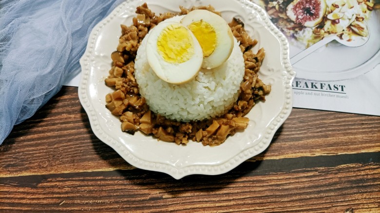 香菇卤肉饭,然后把米饭倒扣在盘子里,浇上香菇卤肉,再放上对半切好的鸡蛋,这道香菇卤肉饭就完成了
