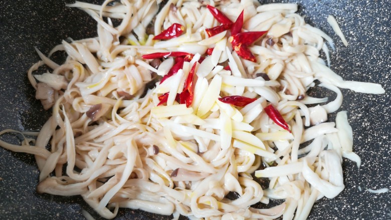 干煸手撕杏鲍菇,放大蒜、生姜和干红辣椒,加入食用油。