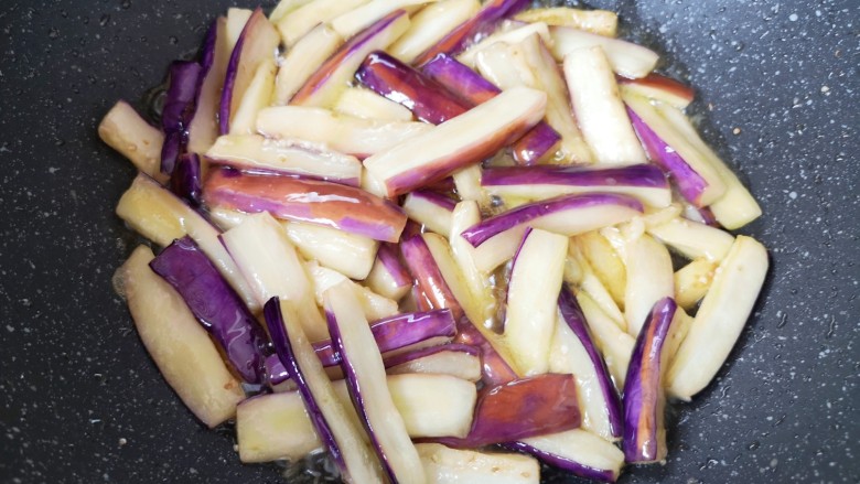 鱼香茄子盖饭,锅里倒多一点食用油烧热,下入茄条煎至变软,盛出备用。