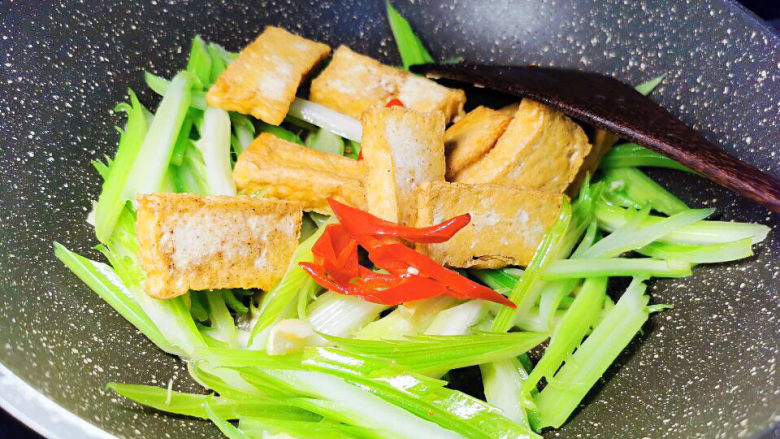 西芹炒香干,下香干与红椒丝,加盐、鸡精调味,翻炒均匀即可