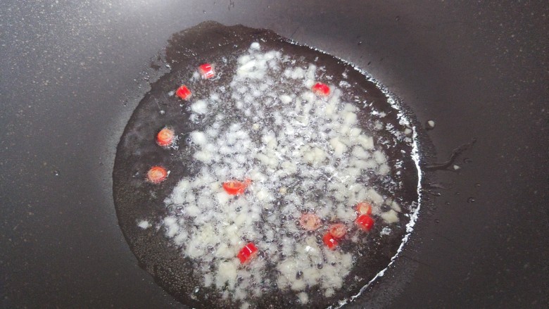 杏鲍菇炒鸡丁,起油锅,油热后,下大蒜末和小米椒,炒香