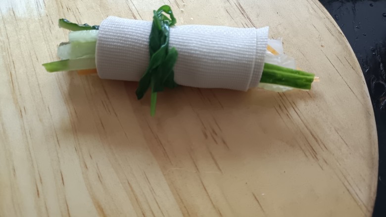 素卷三丝,用千张皮子卷紧它们,用一根韭菜梱着