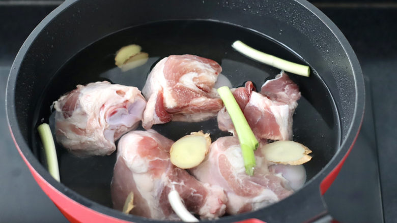 胡萝卜筒骨汤,锅中倒入适量的清水,放入洗净的筒骨,加入葱段和姜片。