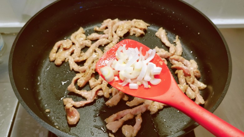 千张肉丝,起油锅放入食用油,油热后放入肉丝翻炒变色,放入大葱去腥增香。