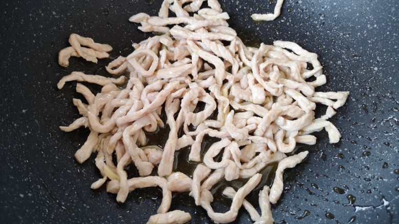 千张肉丝,炒锅内倒适量的食用油烧热,下入腌好的肉丝翻炒至变色。