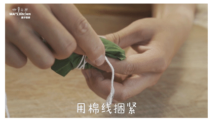 粽子一定要吃咸的|咸蛋黄肉粽最经典,将粽叶翻折包住粽子,用棉线将粽叶捆紧。