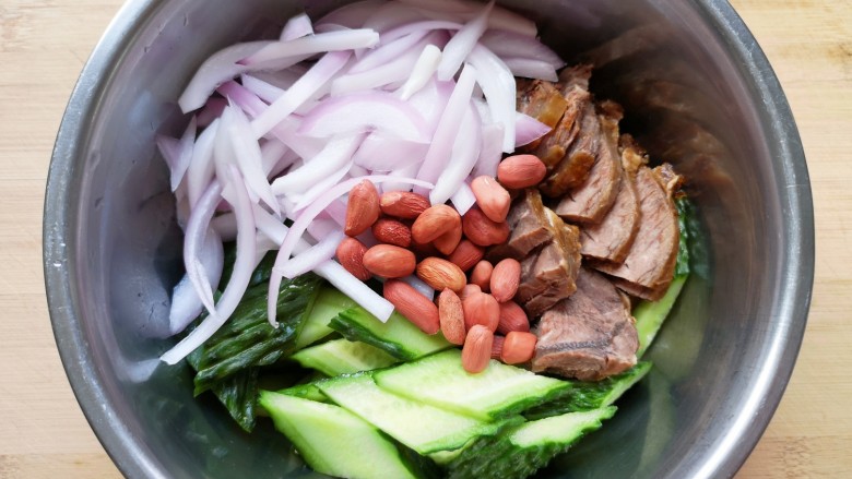 洋葱拌牛肉,将浸泡过的洋葱捞出,控干水分,和黄瓜片、牛肉片一起放入盆里,加入一把熟花生。