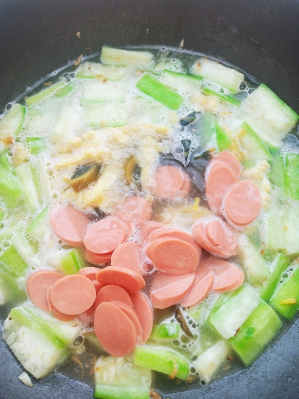 上汤八棱瓜,水开后加入鸡蛋,皮蛋和火腿肠炖煮5分钟。