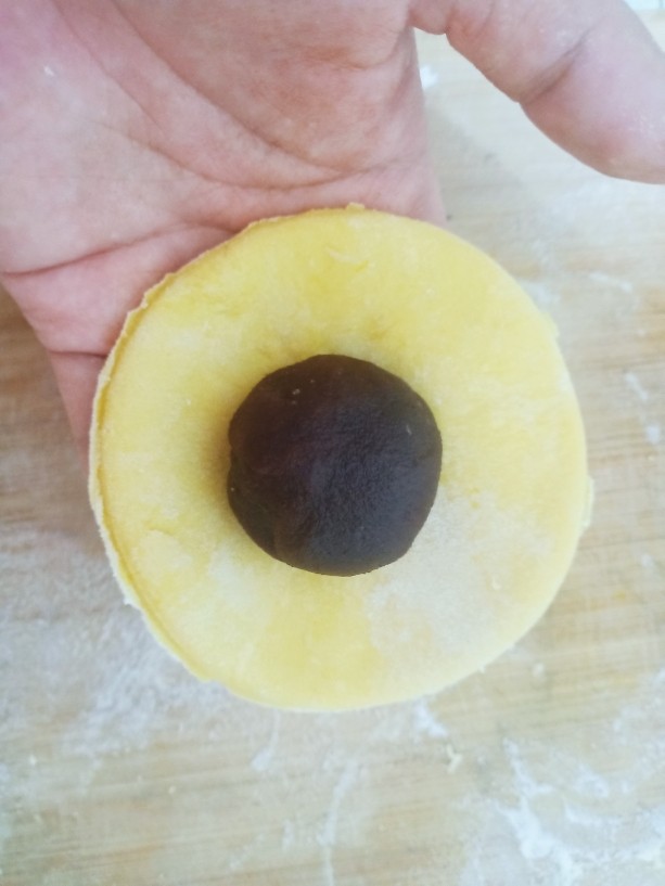 杂粮包子,拿一个小圆饼，放上一个豆沙球。