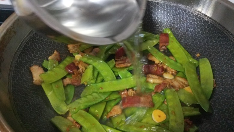 肉片炒荷兰豆,加入一勺水,在加入3克盐炒均匀。
