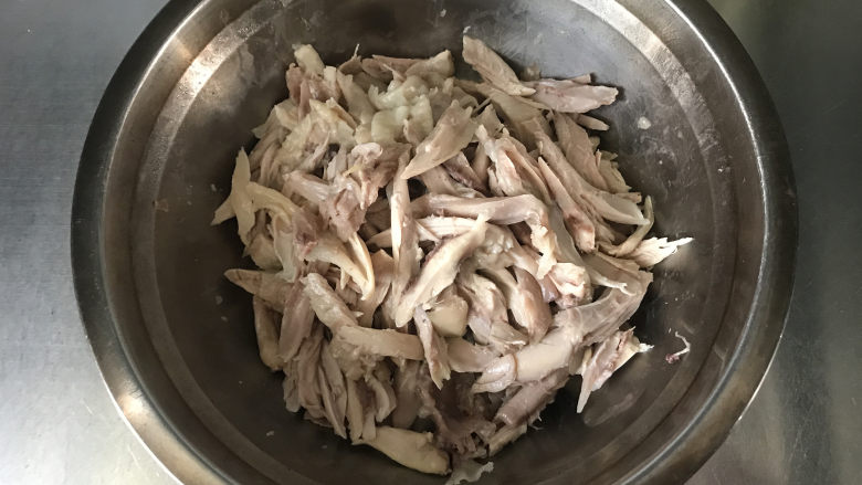椒麻手撕鸡,取出鸡腿,用手把鸡肉撕下来,撕成长条放至盆中;卸下来的鸡骨可重新放回鸡汤中再炖一会儿,汤的味道更浓