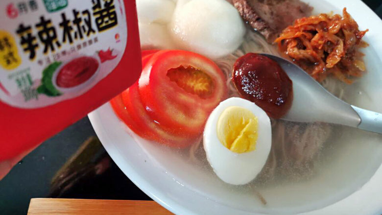 韩式冷面,继续将梨,西红柿,牛排肉,泡菜也放进去,来一勺辣椒酱,撒上芝麻及葱花即可