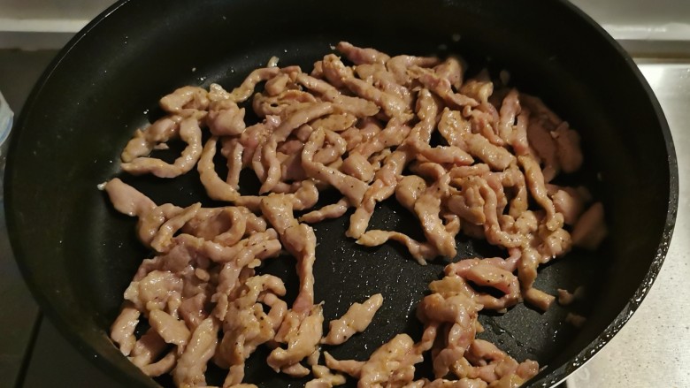 彩椒炒肉丝,再起油锅放入1汤匙食用油,油热后放入肉丝翻炒变色。
